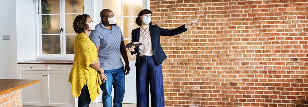 Real estate agent and customer in face mask looking at a home